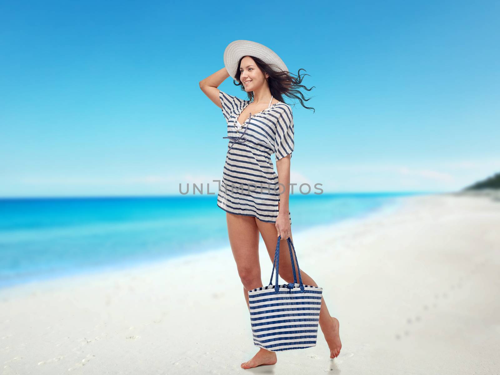 people, fashion, tourism, travel and summer concept - happy young woman in summer clothes and sun hat with bag over beach background