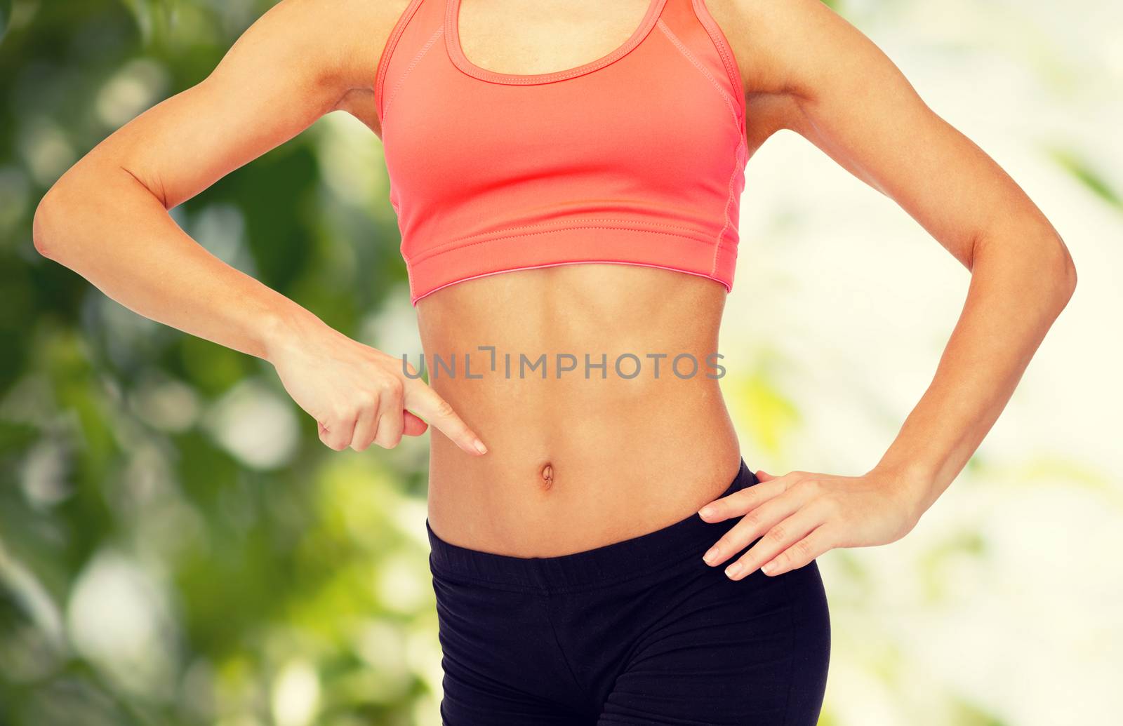 close up of woman pointing finger at her six pack by dolgachov
