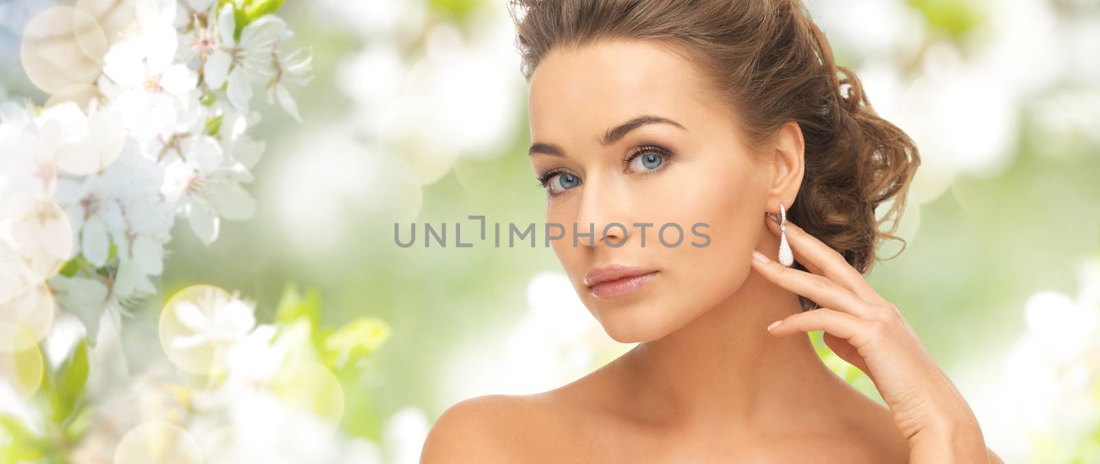 people, beauty, jewelry and accessories concept - beautiful woman with diamond earrings over summer garden and cherry blossom background