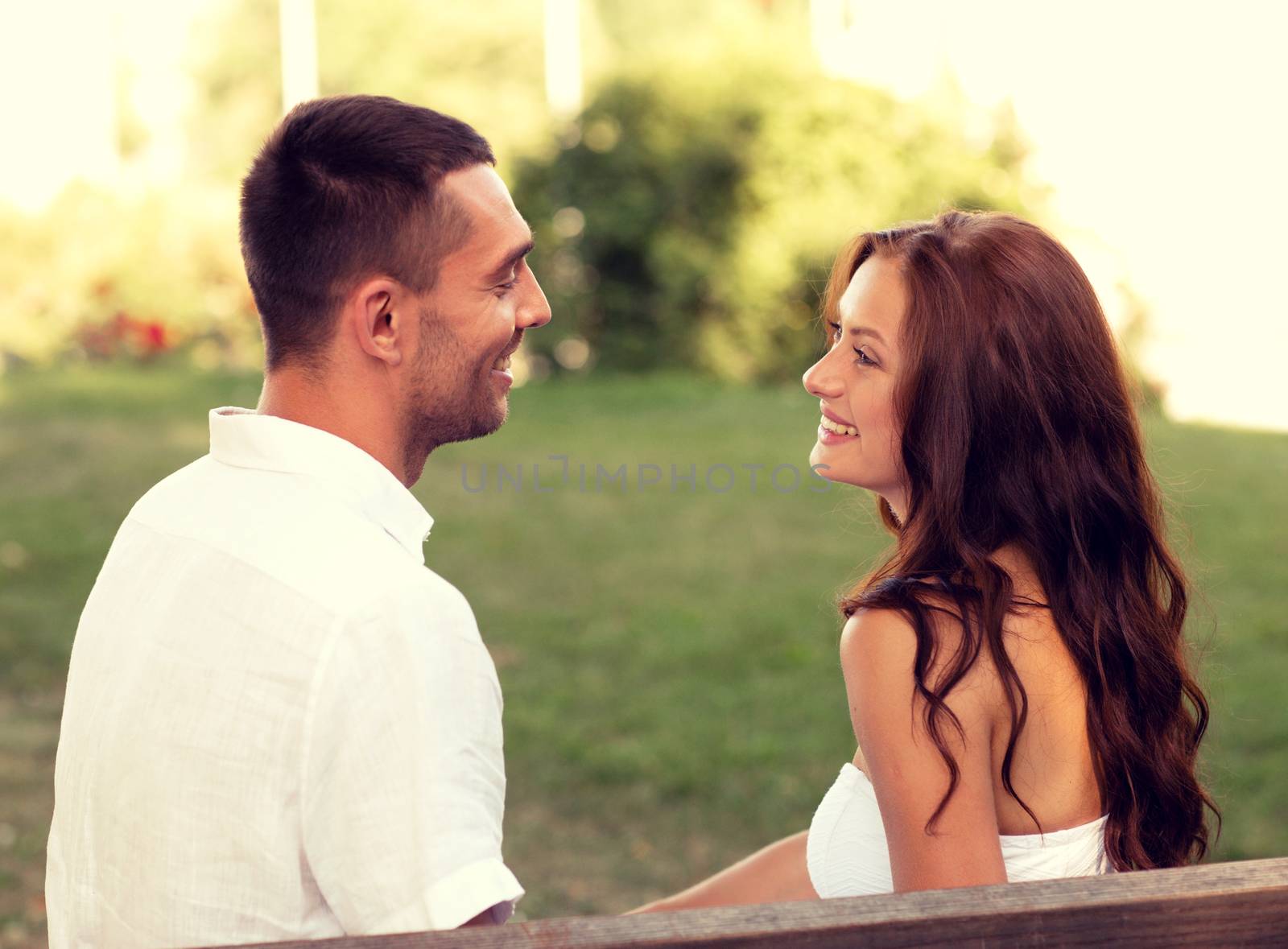 smiling couple sitting on bench in park by dolgachov