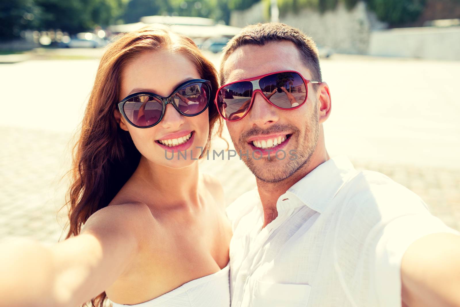 smiling couple wearing sunglasses making selfie by dolgachov