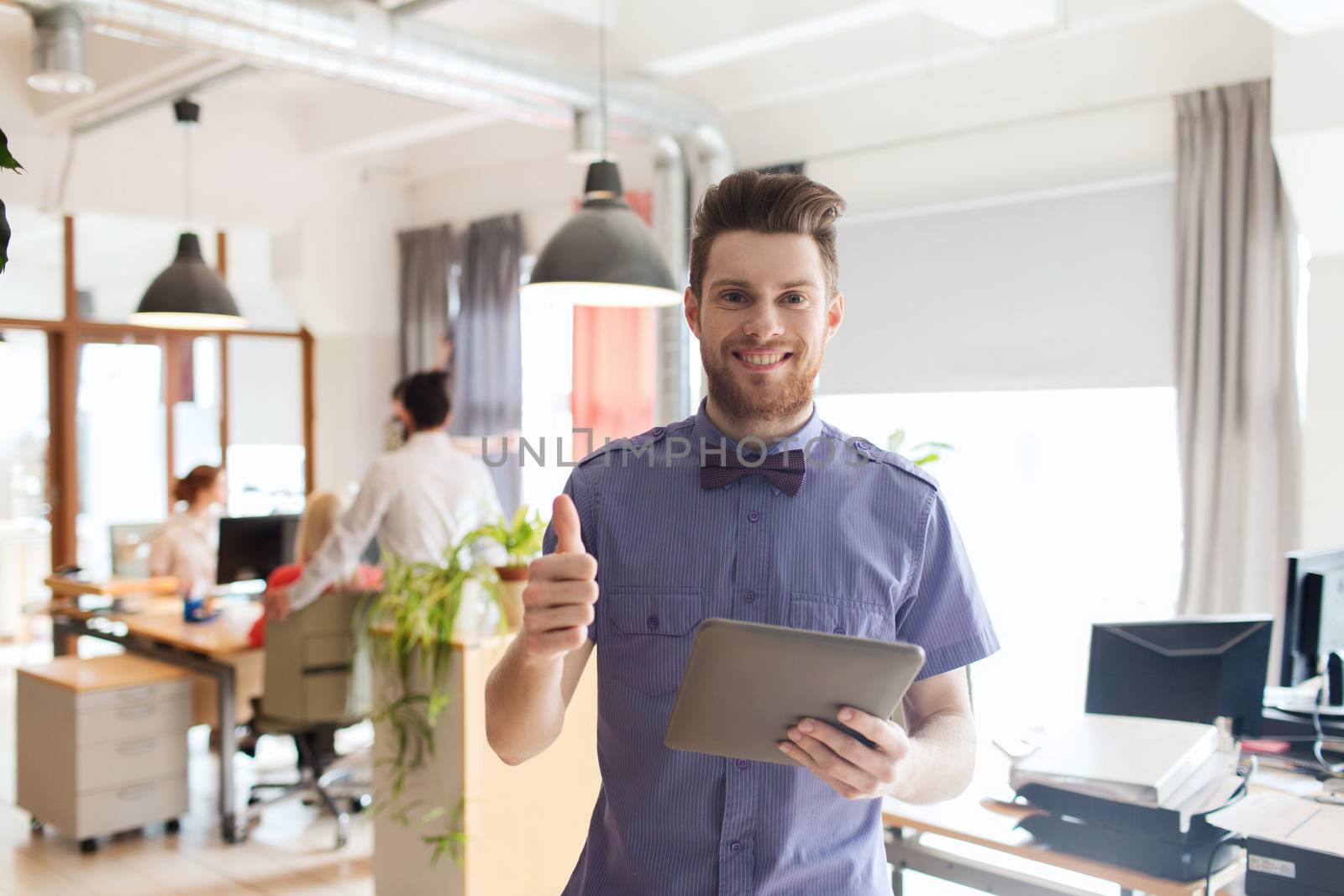 happy creative male office worker with tablet pc by dolgachov