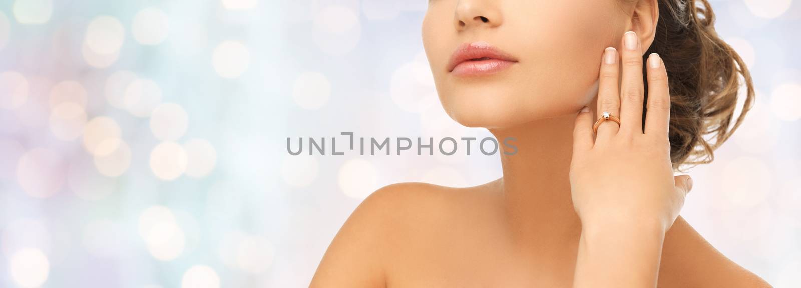 bride, people, jewelry and wedding concept - close up of beautiful woman with diamond engagement ring over blue holidays lights background