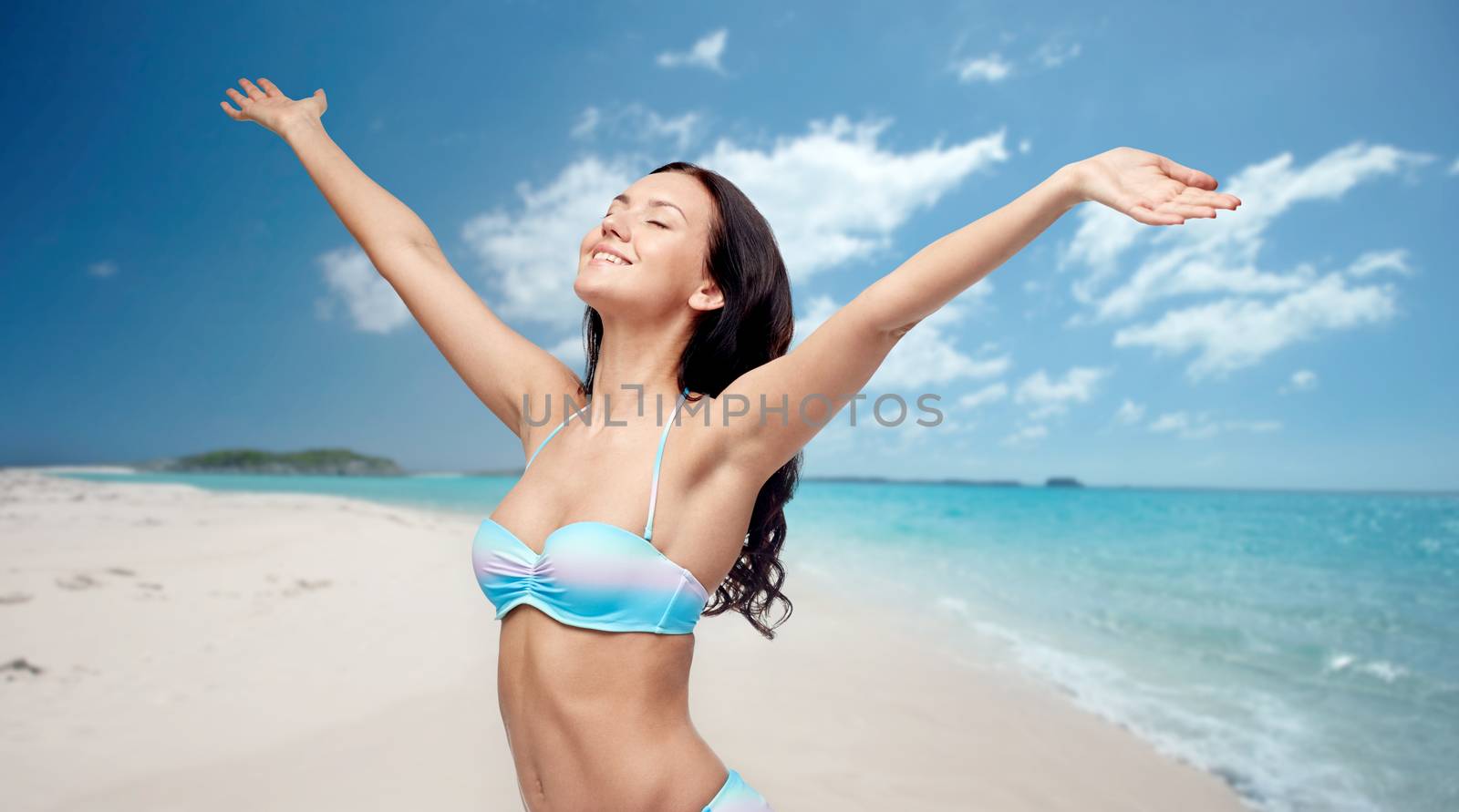 happy woman in bikini swimsuit with raised hands by dolgachov