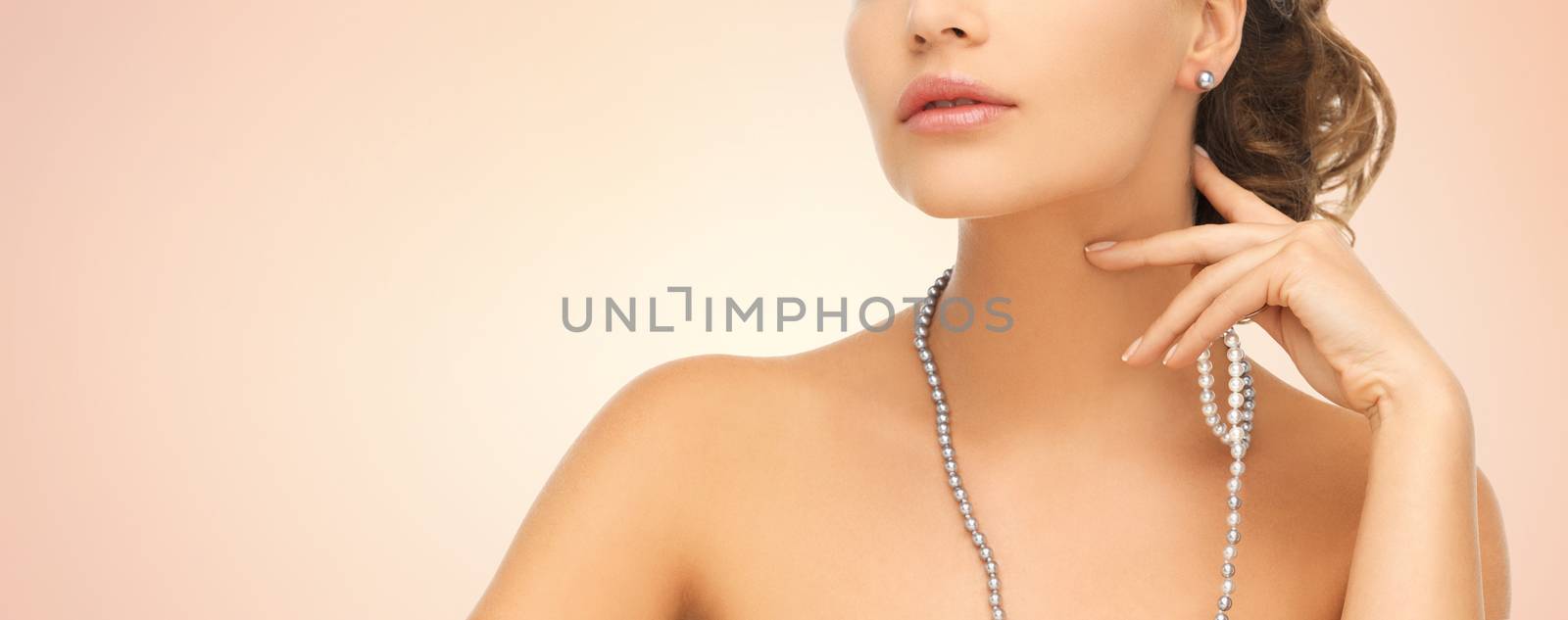 fashion, style, jewelry, beauty and people concept - beautiful woman wearing pearl earrings and necklace over beige background