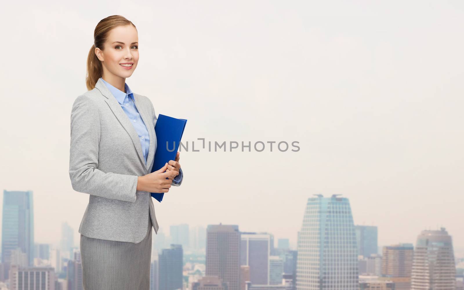 business, people and education concept - smiling young businesswoman with holding over city background
