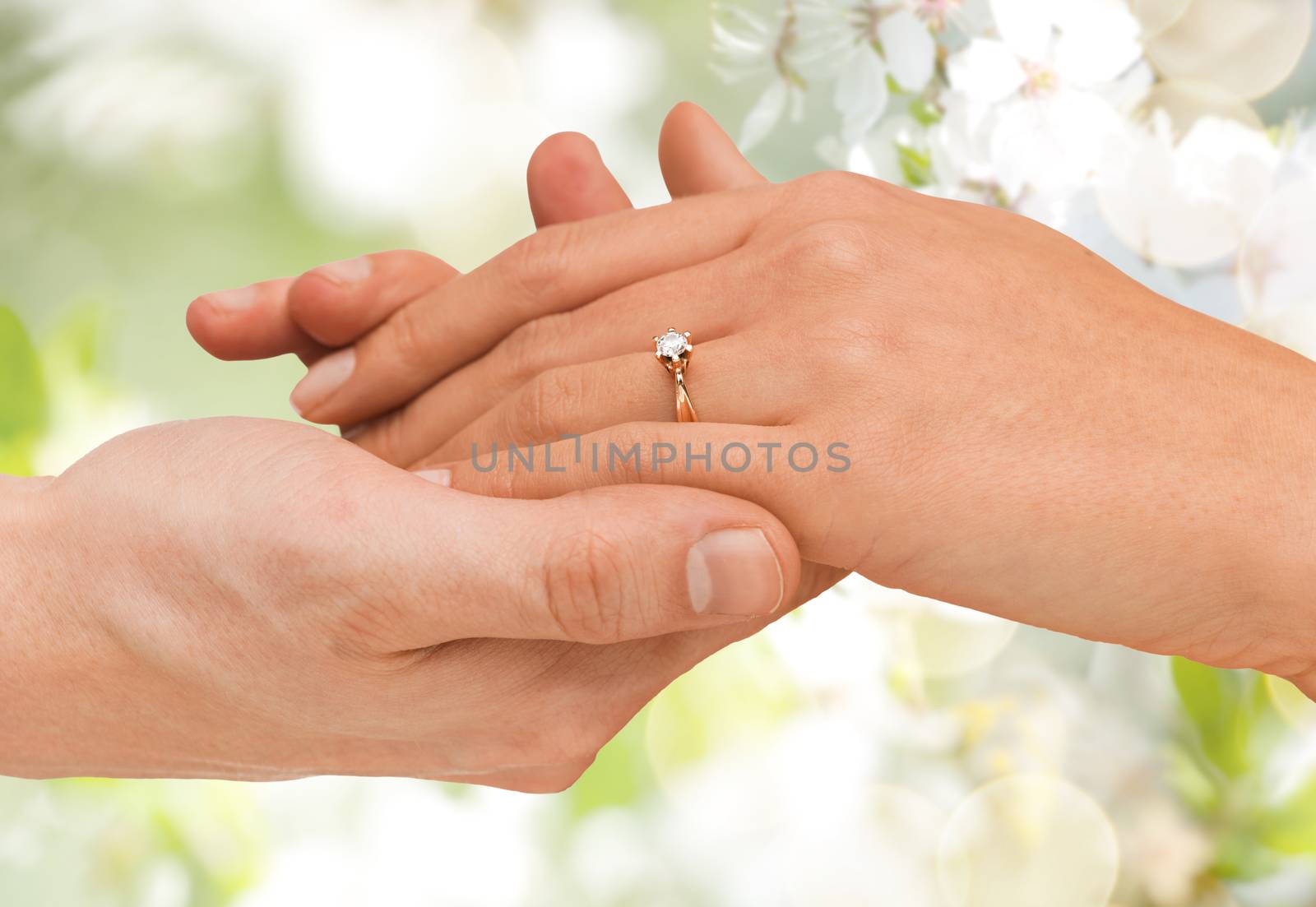 jewelry, couple, love and wedding concept - close up of man and woman hands with engagement ring over summer garden and cherry blossom background