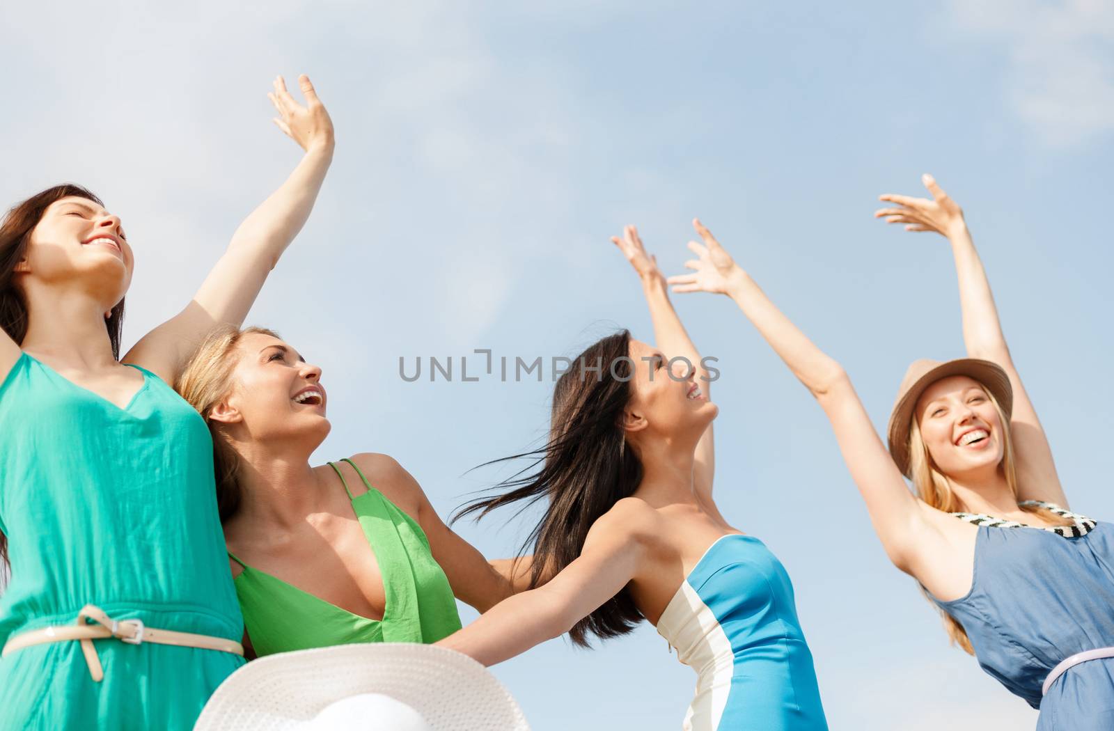 summer holidays and vacation concept - smiling girls with hands up on the beach