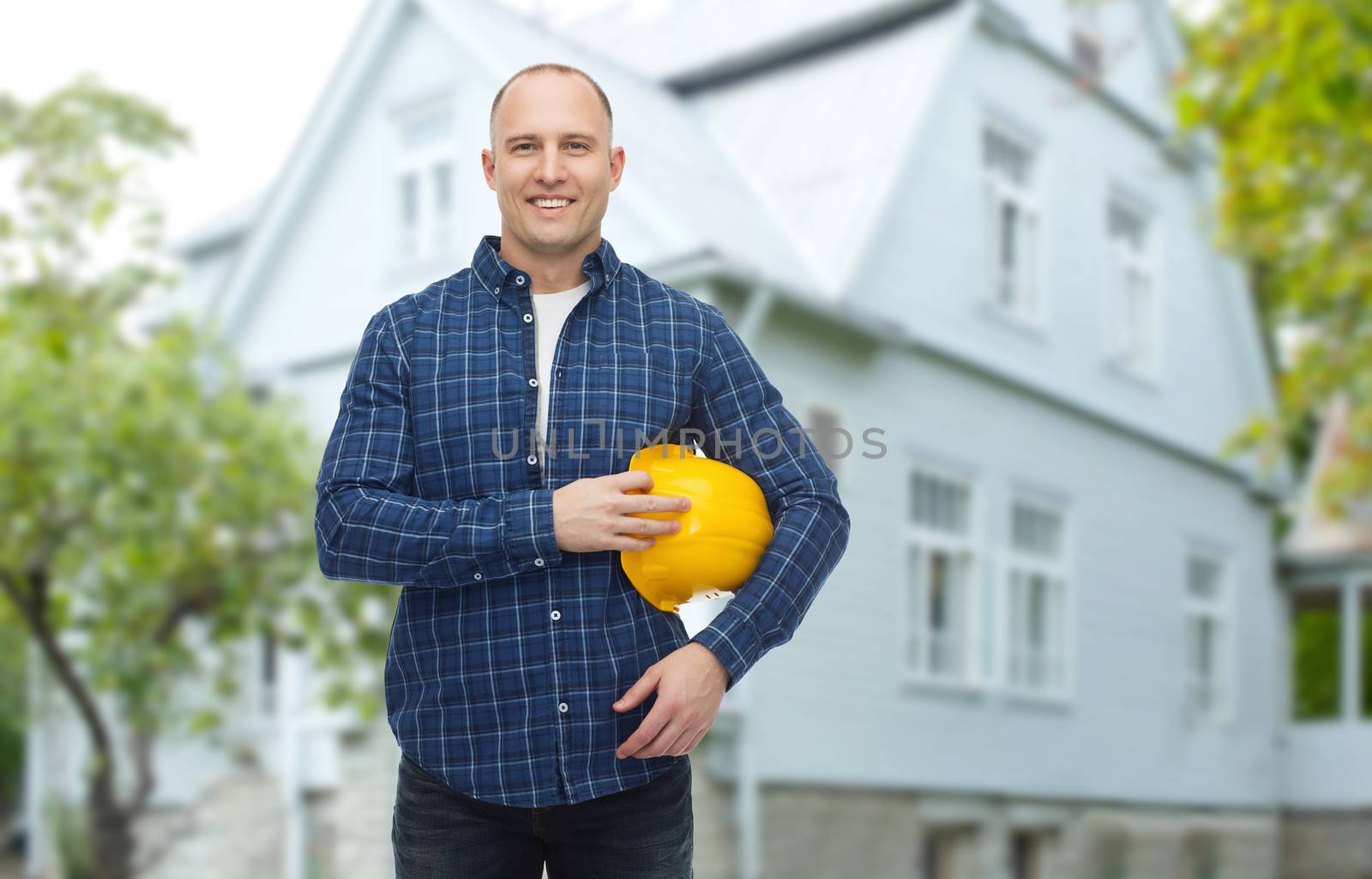 repair, building, construction and maintenance concept - smiling man holding helmet over living house background