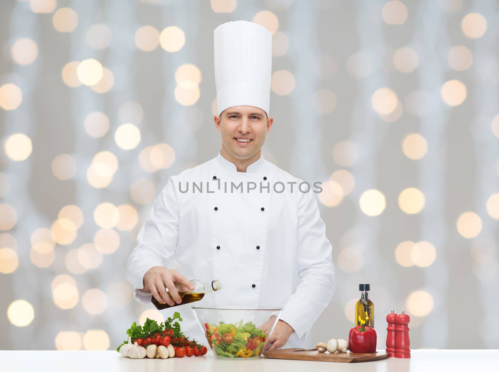 profession, vegetarian, food and people concept - happy male chef cooking vegetable salad over christmas holidays lights background