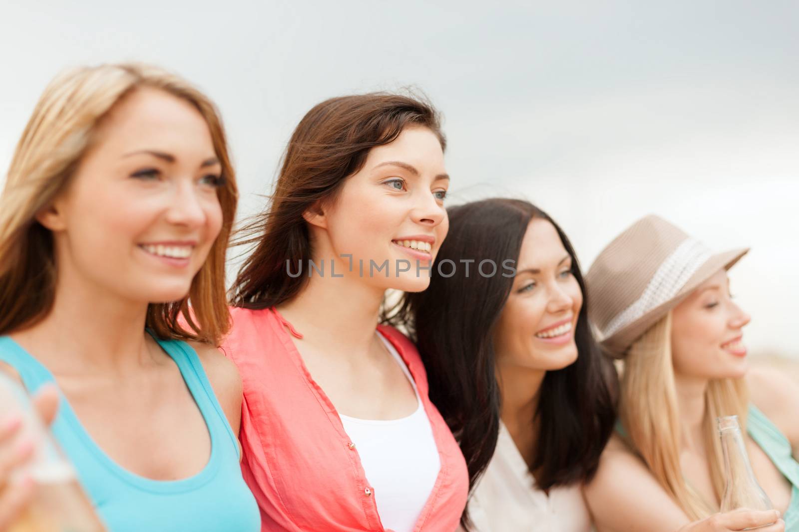 smiling girls with drinks on the beach by dolgachov