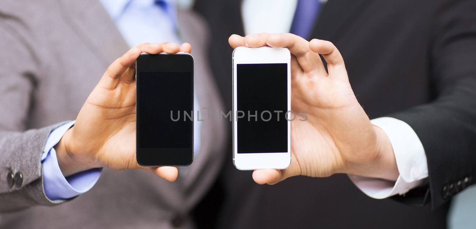 business, technology, internet and office concept - businessman and businesswoman with blank black smartphone screens in office