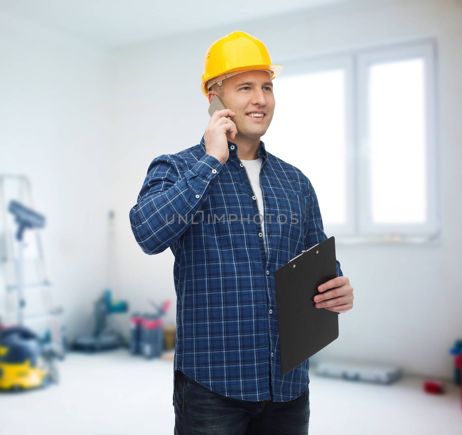 construction, building, people, technology and maintenance concept - smiling male builder or manual worker in helmet with clipboard calling on smarphone over room with work equipment background