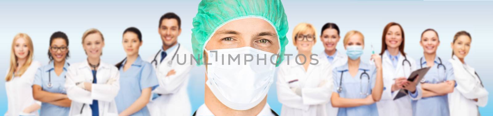people, medicine and health care concept - surgeon in medical cap and mask over group of medics on blue background