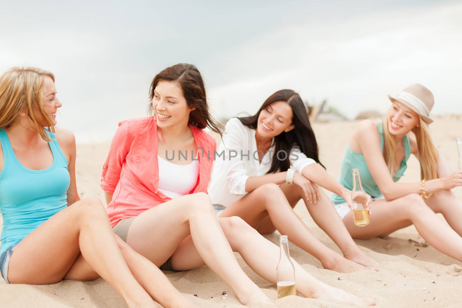 smiling girls with drinks on the beach by dolgachov