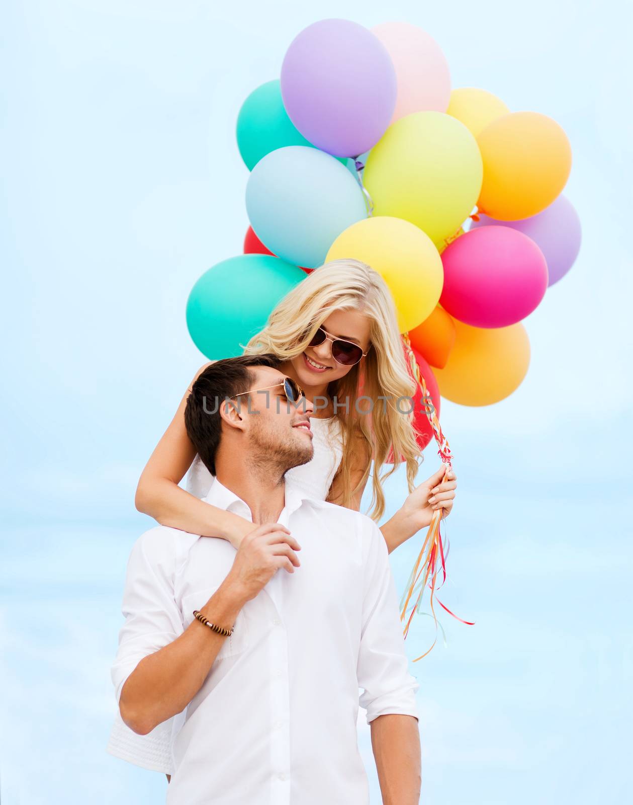 couple with colorful balloons at seaside by dolgachov