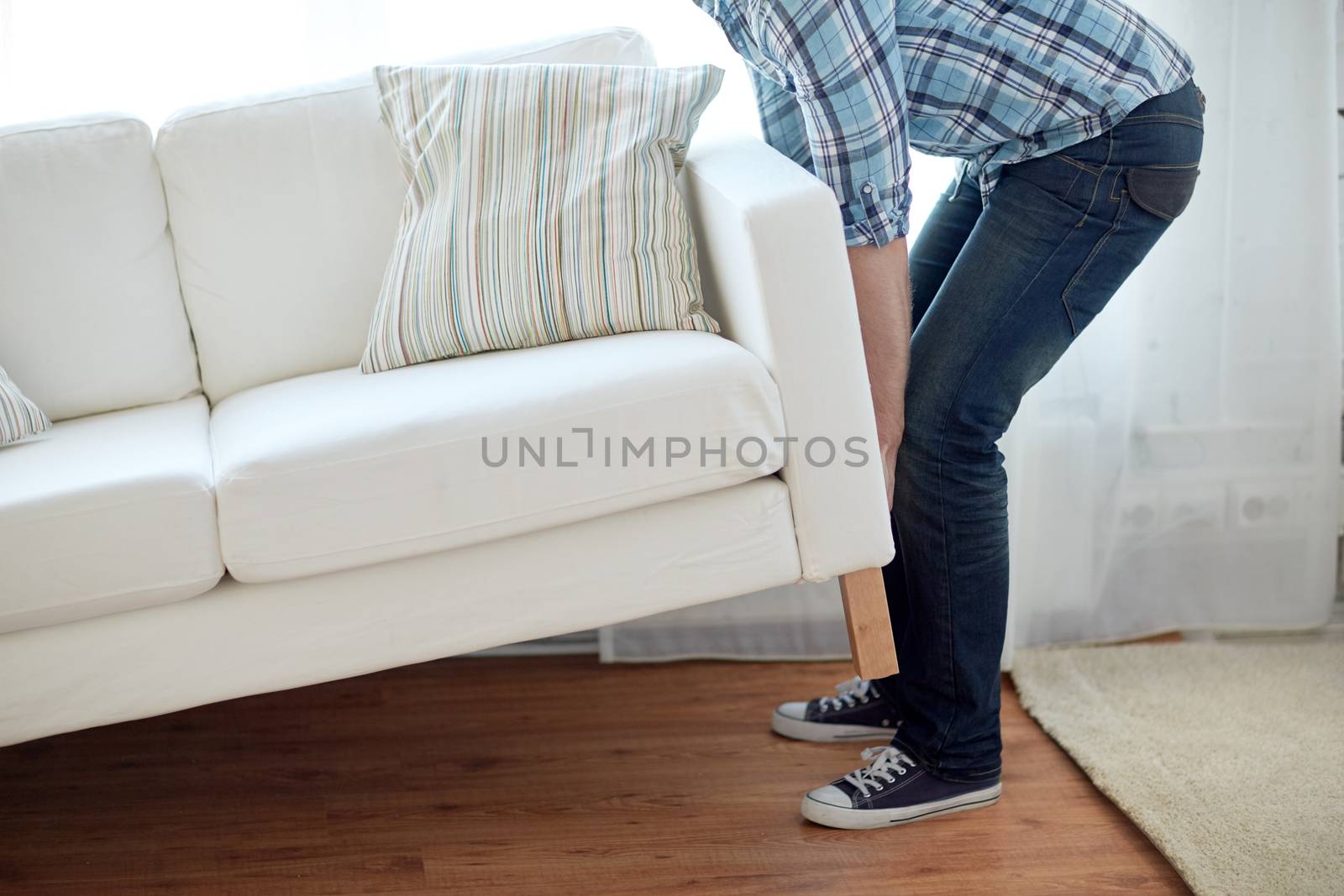 new home, real estate, moving and furniture concept - close up of male lifting up sofa or couch