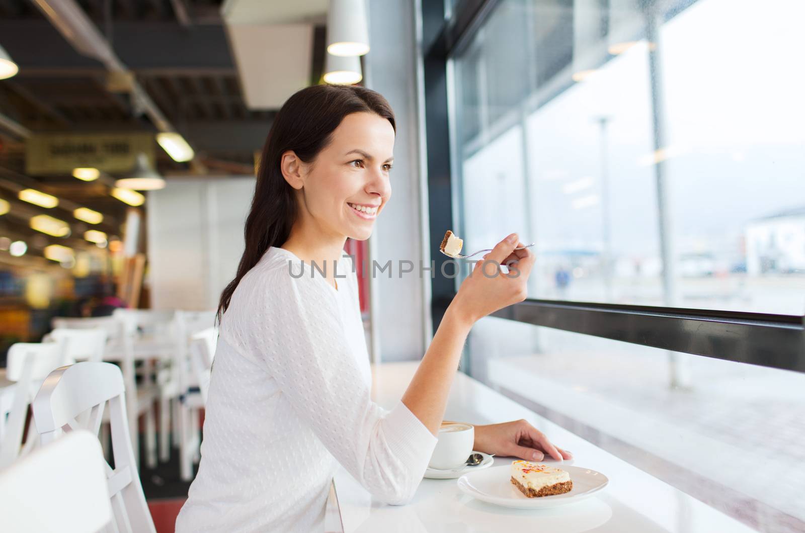 smiling young woman with cake and coffee at cafe by dolgachov