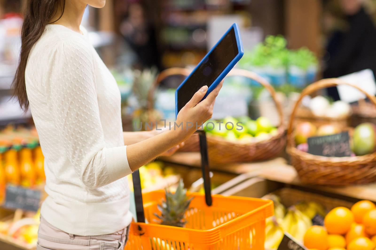 sale, shopping, consumerism and people concept - close up of young woman with food basket and tablet pc computer in market