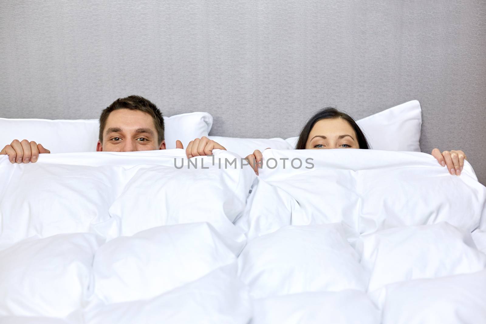 people, bedtime, comfort and relations concept - concept - happy couple hiding under blanket in bed