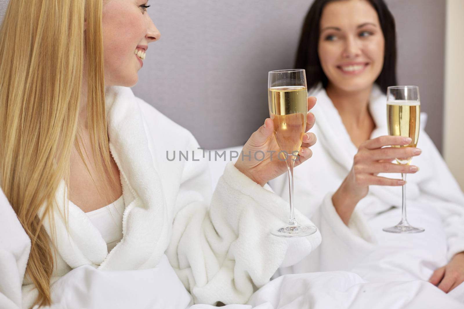 happy women in bathrobes with champagne glasses by dolgachov