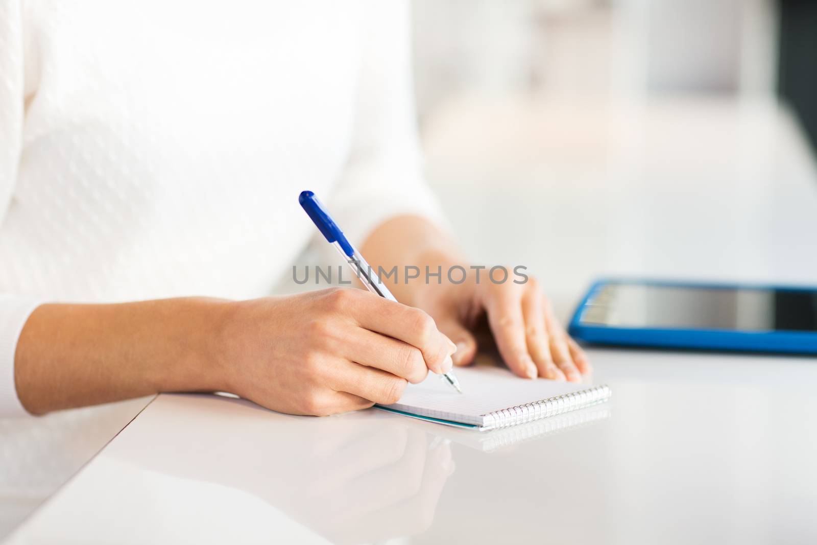 close up of hands with pen writing to notepad by dolgachov