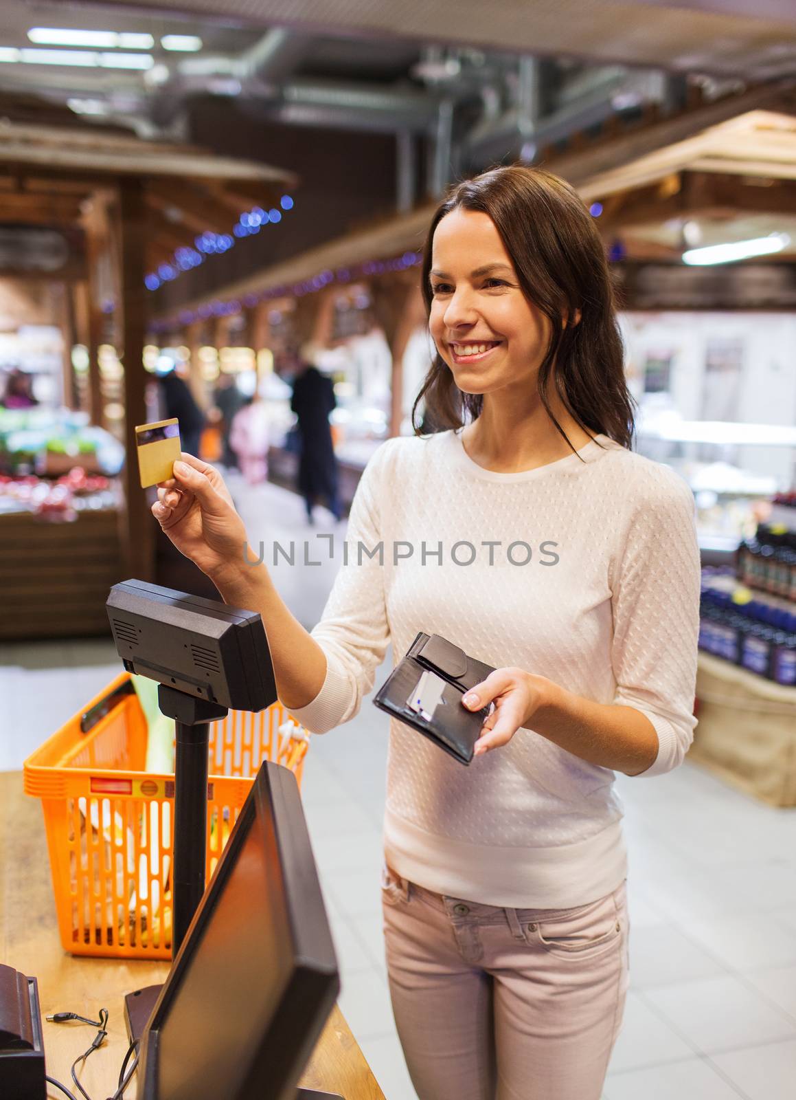happy woman with credit card buying food in market by dolgachov