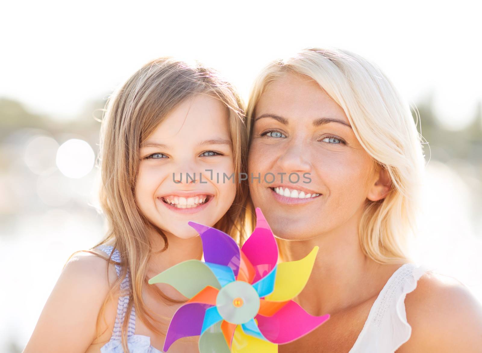 happy mother and child girl with pinwheel toy by dolgachov