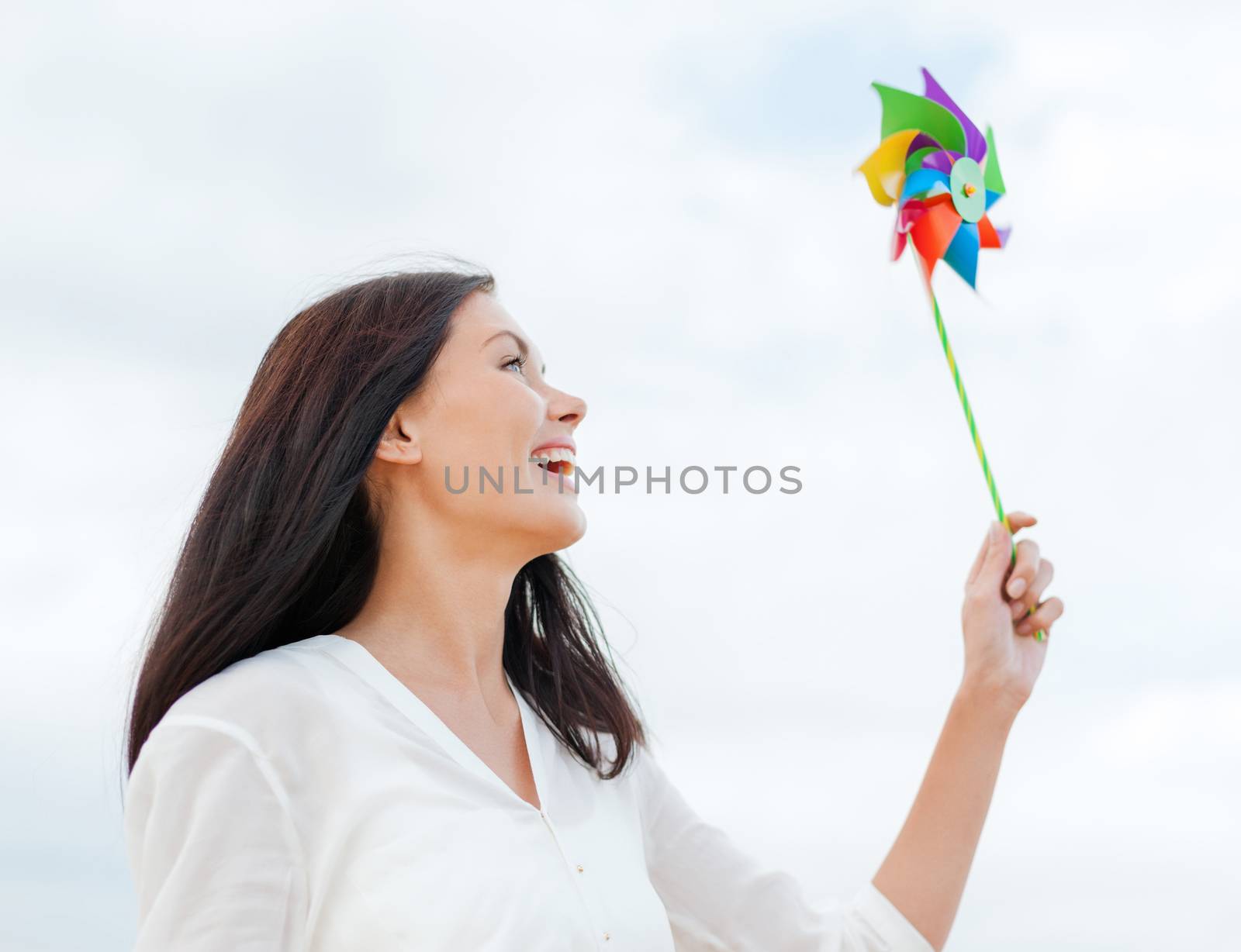 summer holidays, vacation and ecology concept - girl with windmill toy on the beach