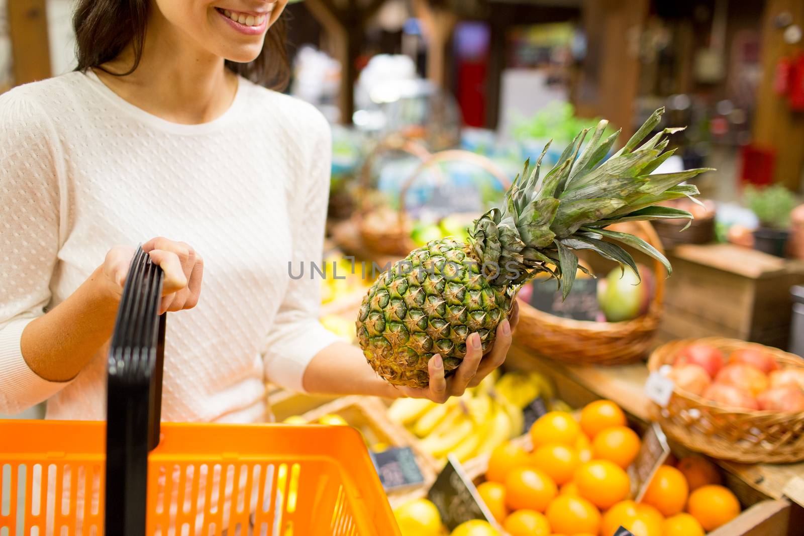 sale, shopping, consumerism and people concept - close up of young woman with food basket and pineapple in grocery market