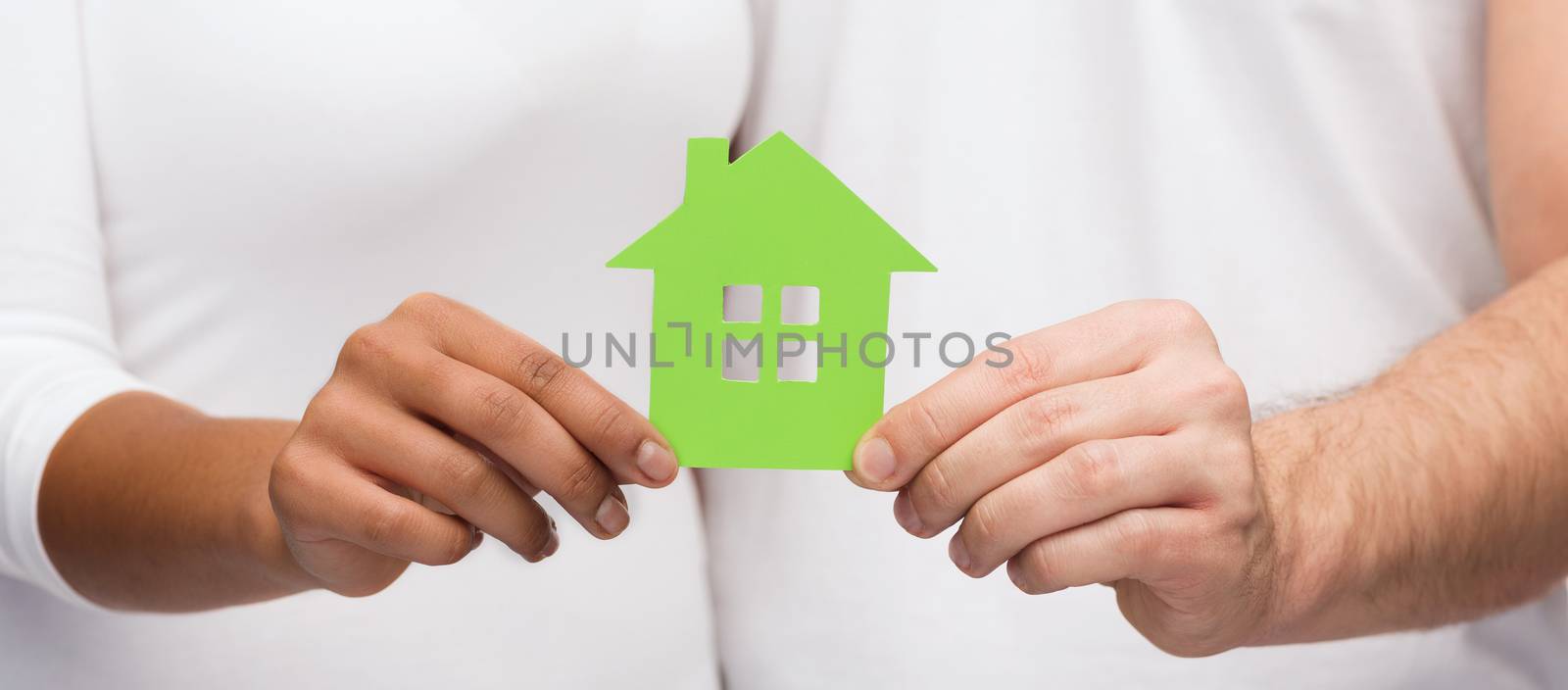 real estate, family and eco concept - closeup picture of couple hands holding green house