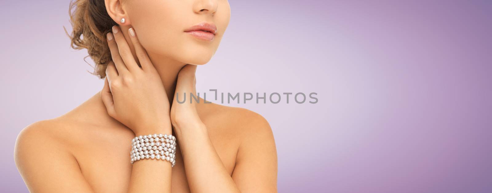 beauty, people and jewelry concept - close up of beautiful woman with pearl earrings and bracelet over violet background