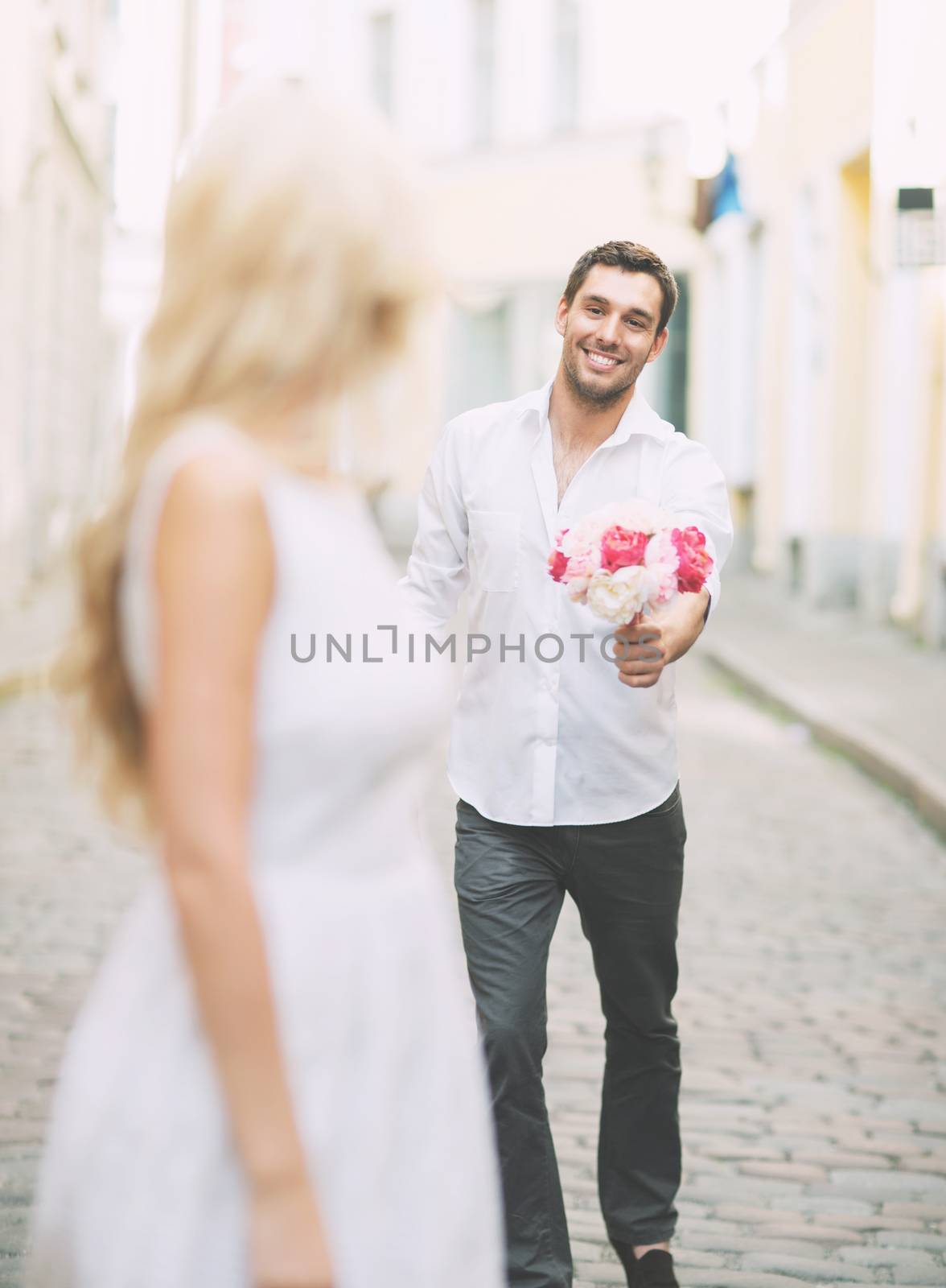 summer holidays and dating concept - couple with bouquet of flowers in the city
