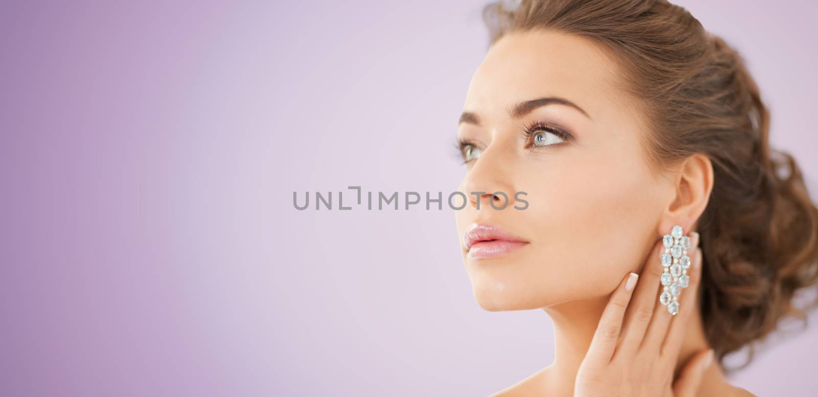 people, beauty, jewelry and accessories concept - beautiful woman with diamond earrings over violet background