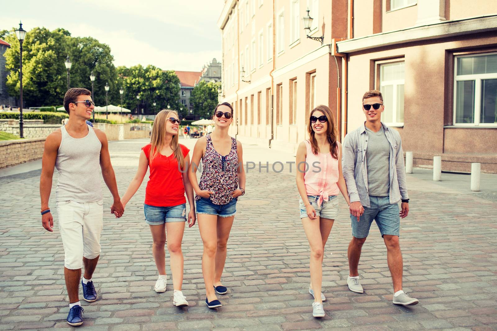 friendship, travel, tourism, summer vacation and people concept - group of smiling teenagers walking in the city