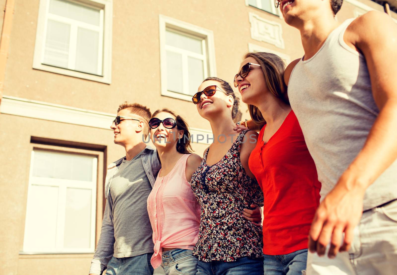 friendship, leisure, summer, gesturer and people concept - group of smiling friends walking in city