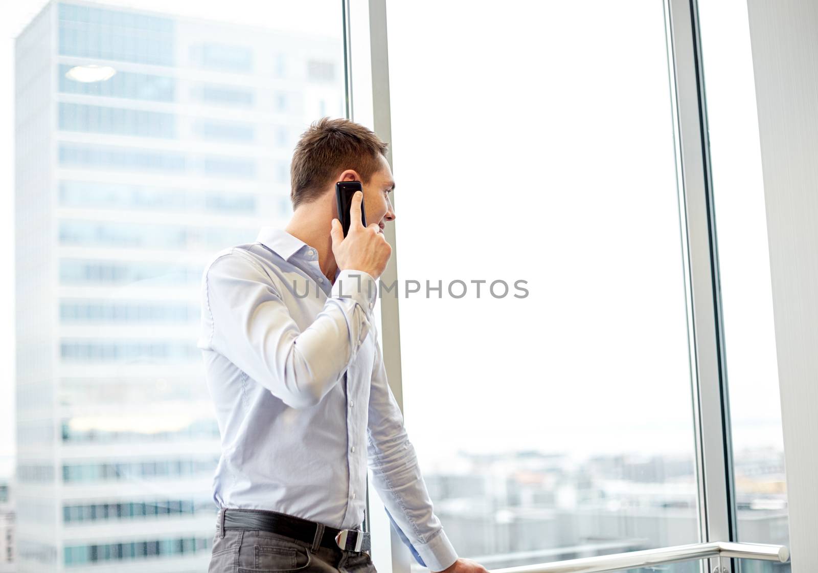 happy businessman calling on smartphone in office by dolgachov