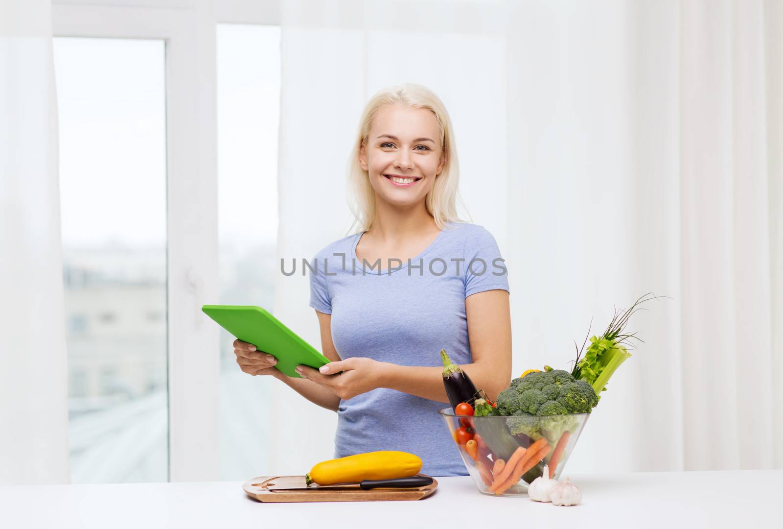 smiling young woman with tablet pc cooking at home by dolgachov