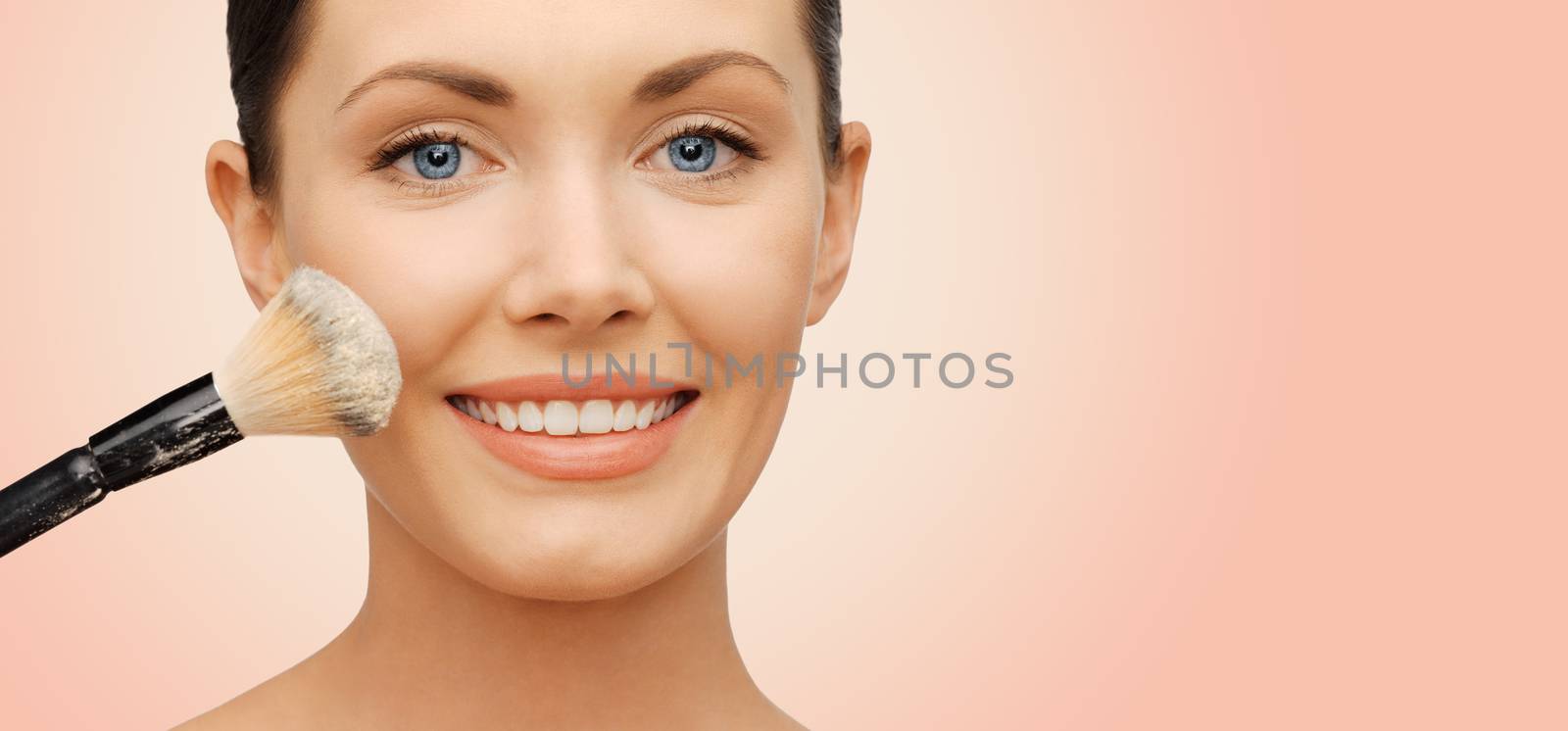 happy woman applying powder foundation with brush by dolgachov