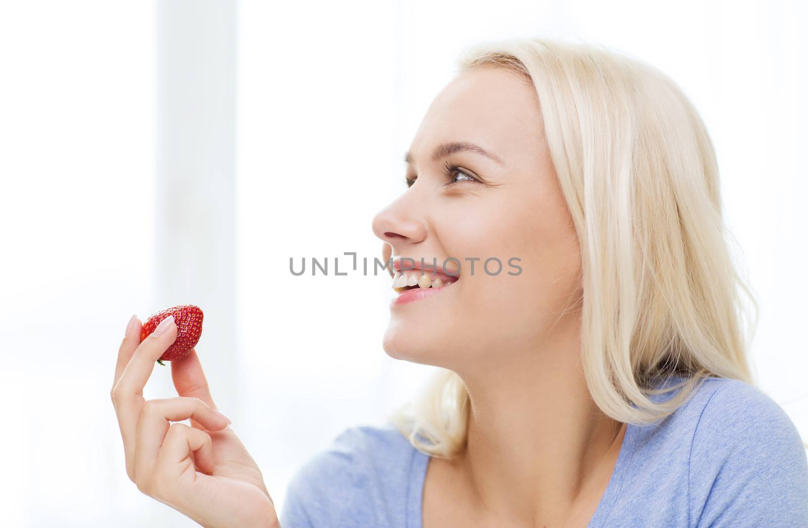 happy woman eating strawberry at home by dolgachov