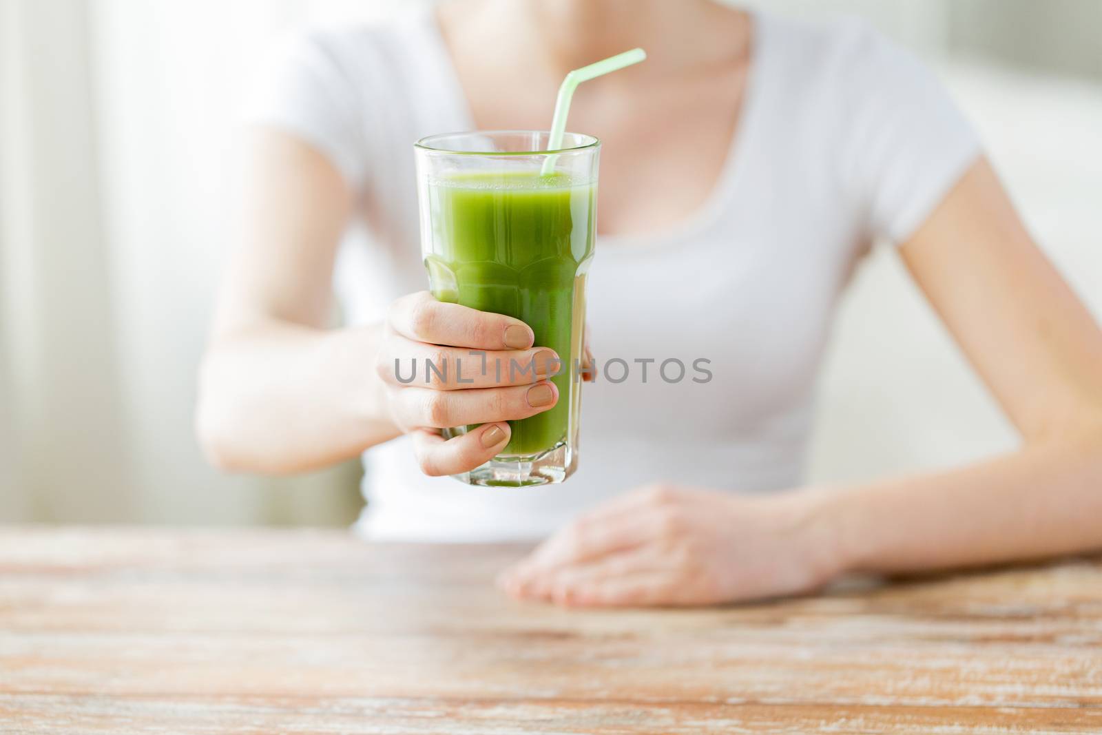 close up of woman hands with green juice by dolgachov