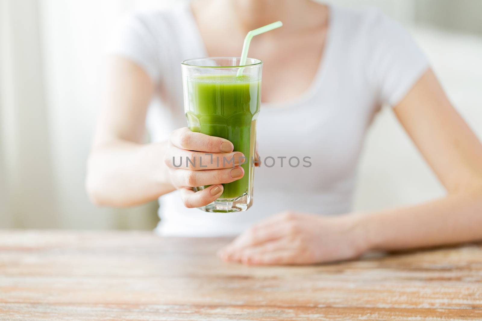 healthy eating, food, diet, detox and people concept - close up of woman hands with green juice on wooden table