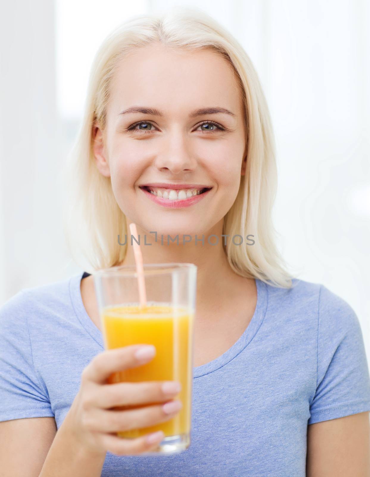 smiling woman drinking orange juice at home by dolgachov