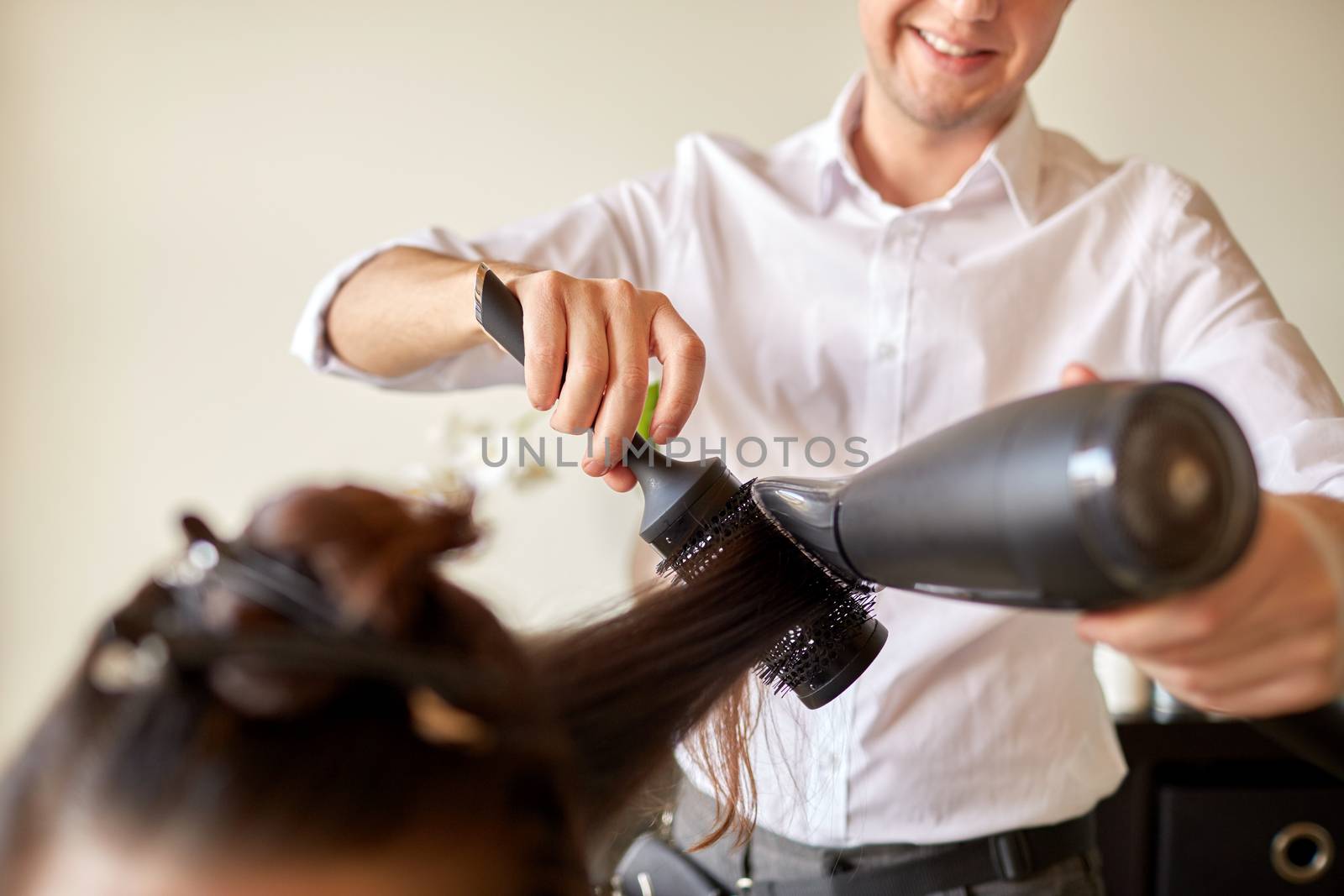 beauty, hairstyle, blow-dry and people concept - close up of woman and hairdresser with fan and brush making hot styling at hair salon