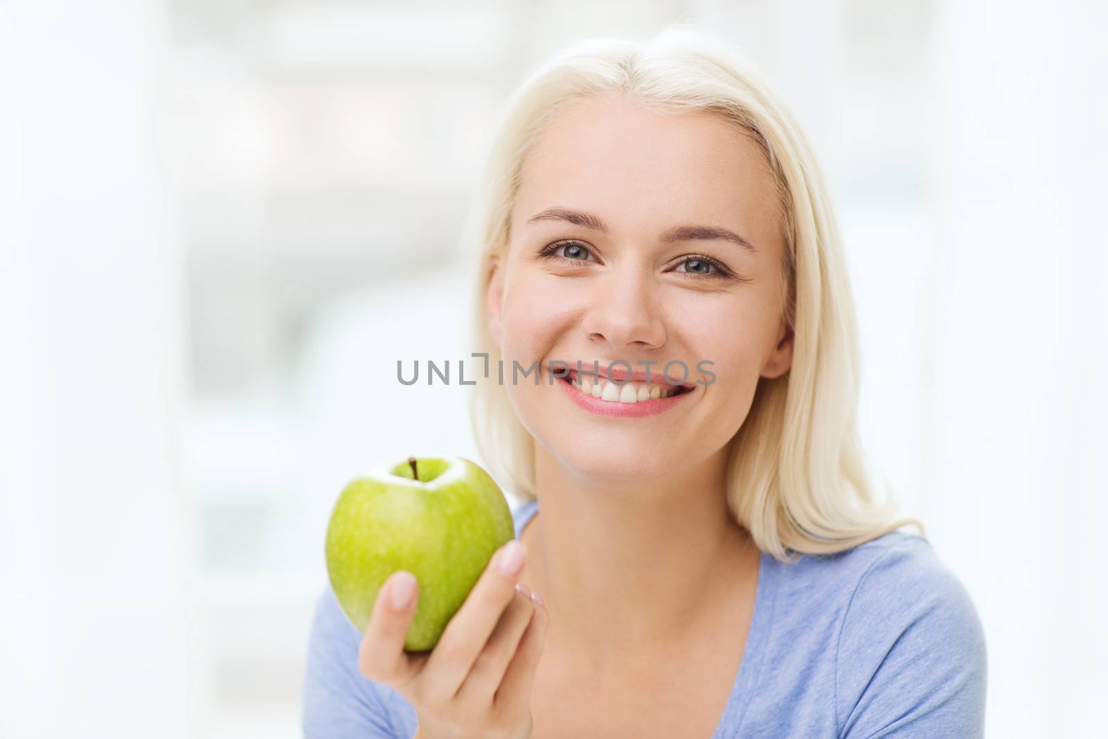 happy woman eating green apple at home by dolgachov