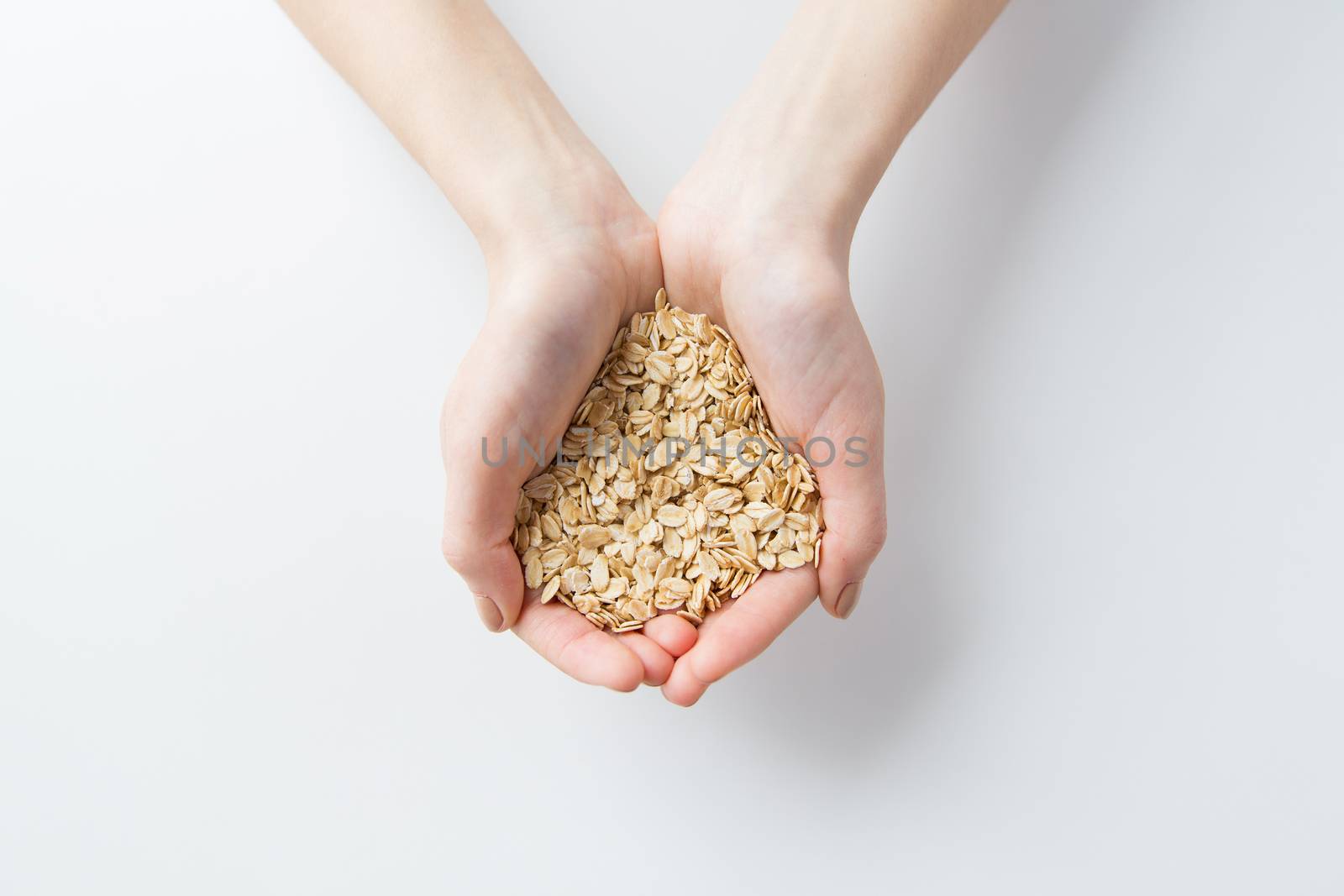 close up of woman hands holding oatmeal flakes by dolgachov
