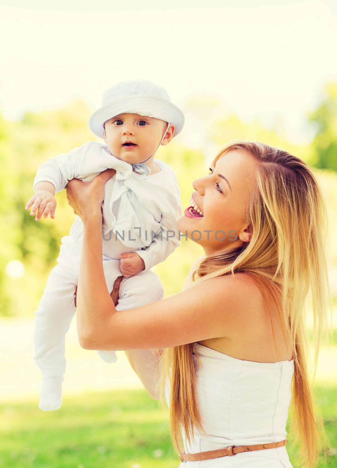 family, child, happiness and motherhood concept - happy mother with little baby sitting on blanket in park