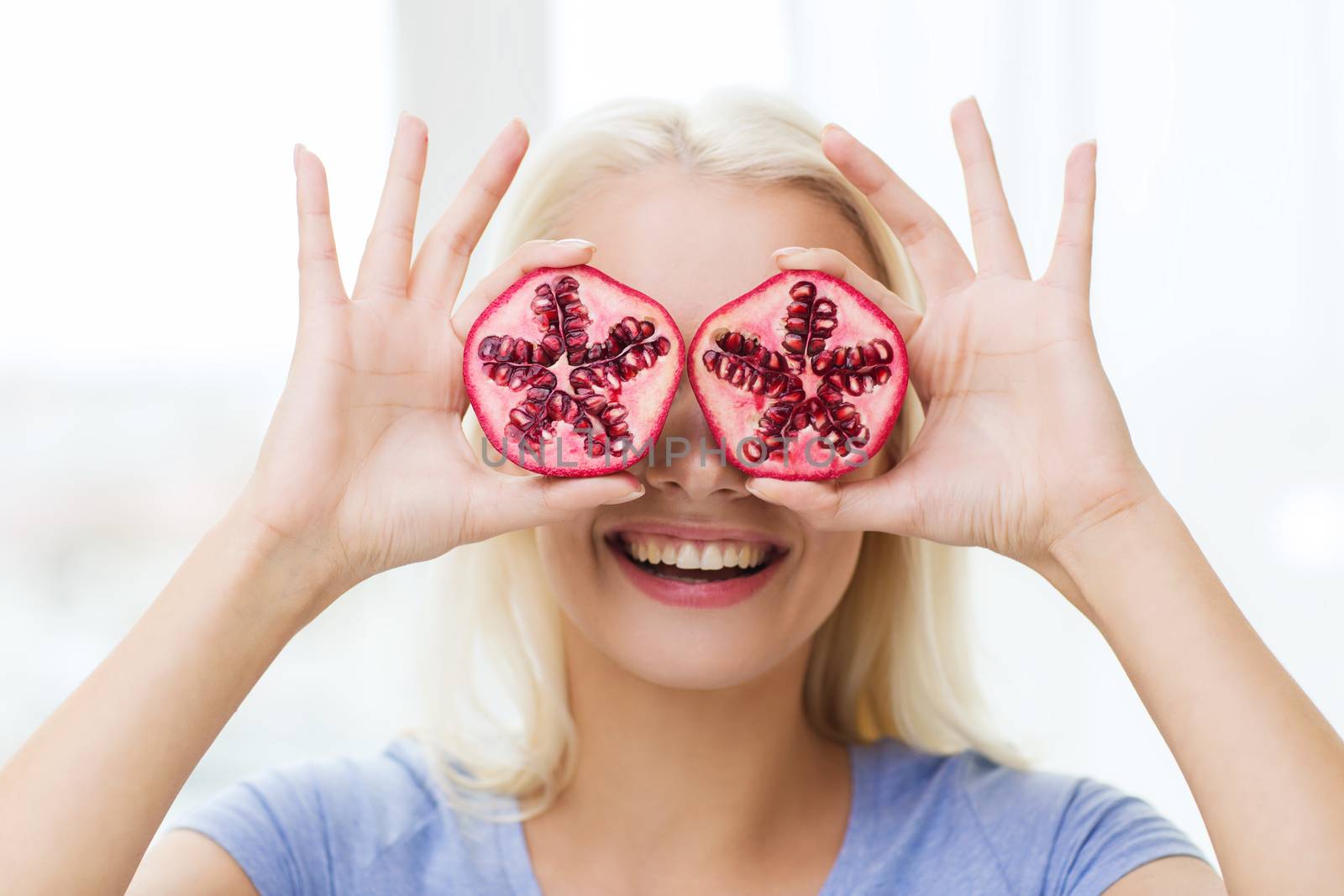 healthy eating, organic food, fruit diet, comic and people concept - happy woman having fun and covering her eyes with pomegranate