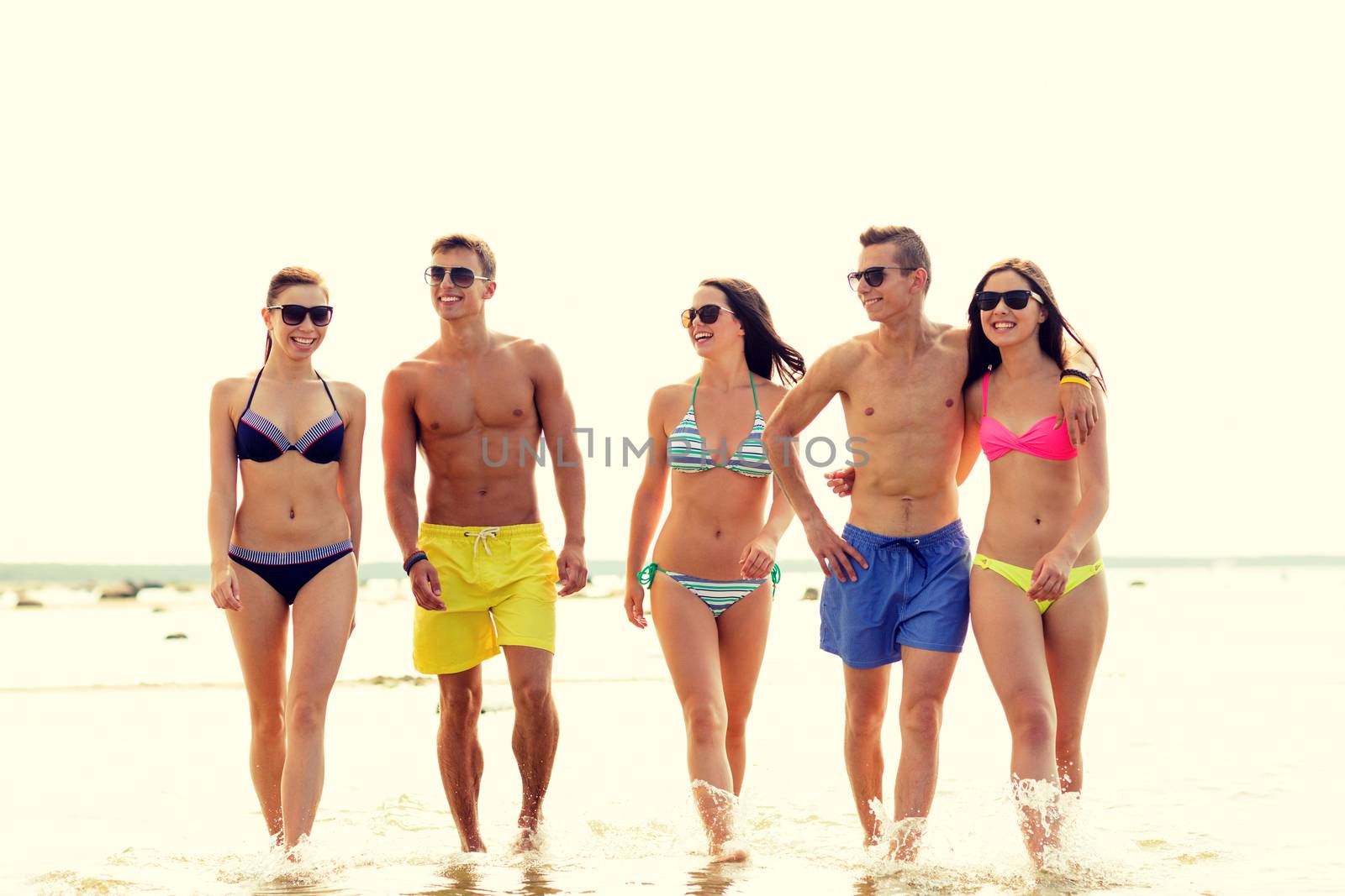 smiling friends in sunglasses on summer beach by dolgachov