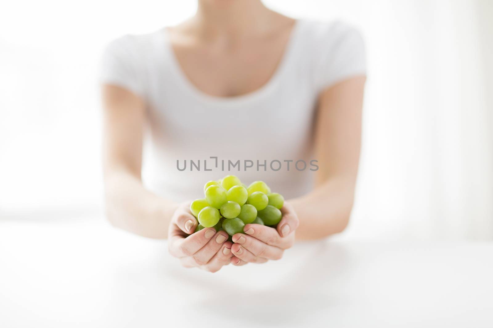 close up of woman hands holding green grape bunch by dolgachov